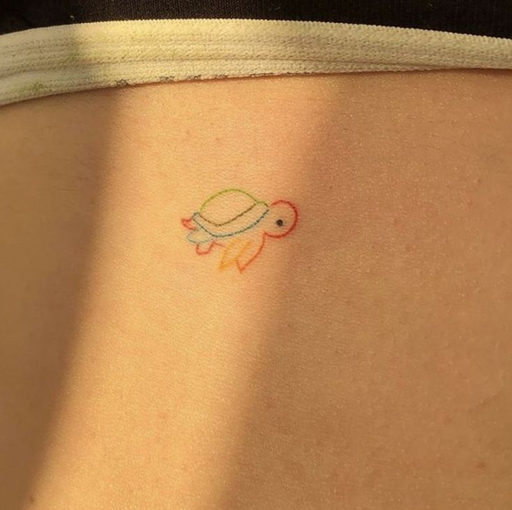 a small turtle tattoo on the back of a woman's stomach