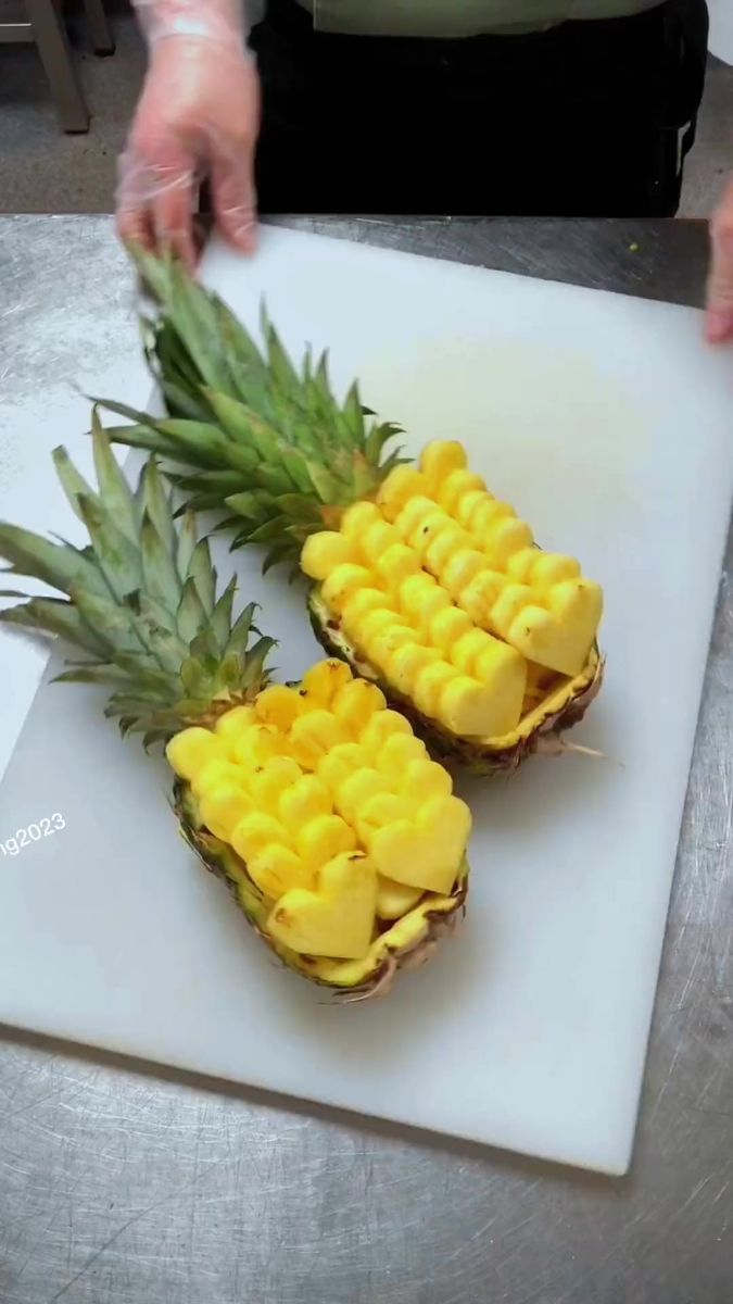 two pineapple halves cut into pieces on a cutting board