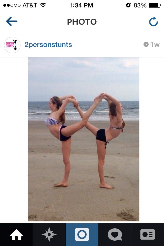 two women doing yoga on the beach with their hands in the shape of a heart