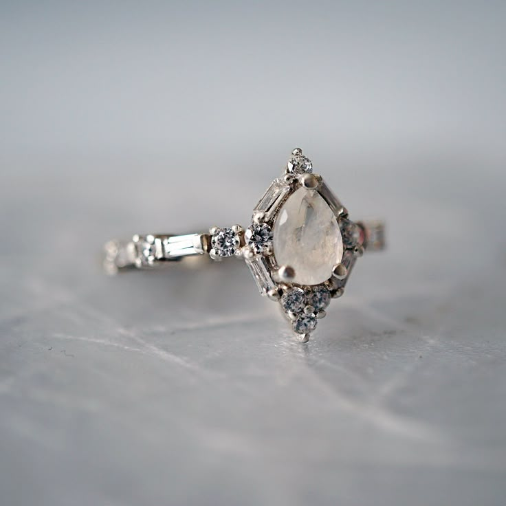 a white diamond ring sitting on top of a table