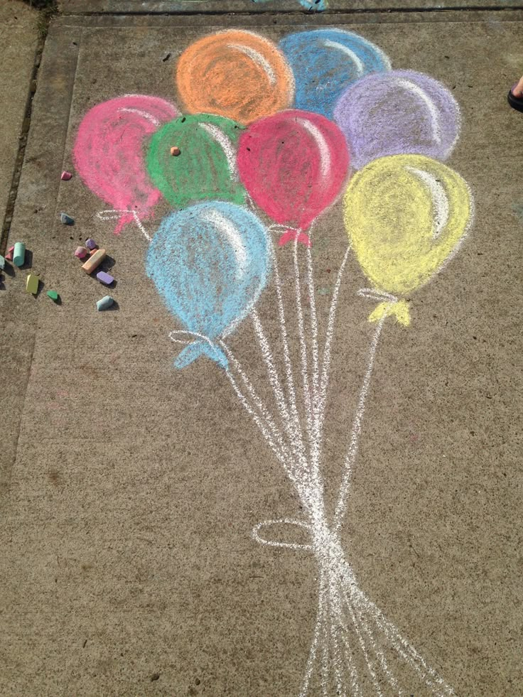 chalk drawing of balloons on the sidewalk with crayons