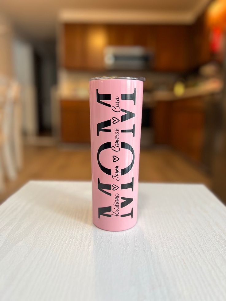 a pink tumbler sitting on top of a white table in a room with wooden floors