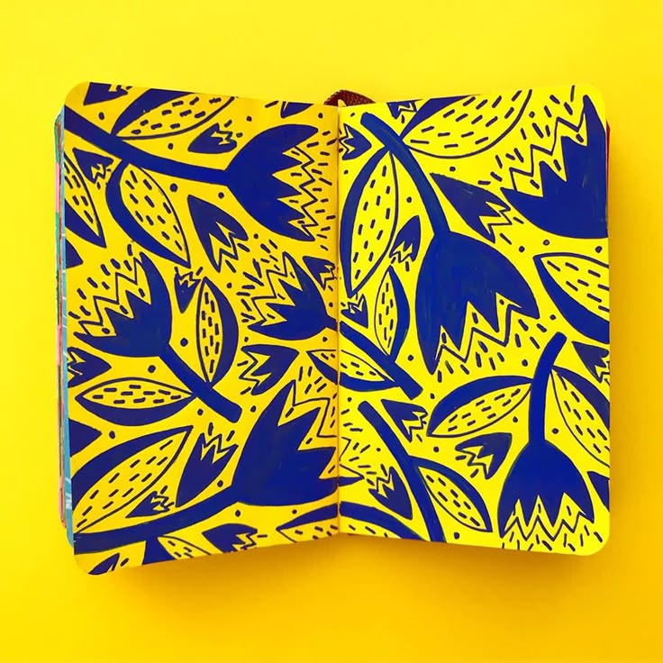 a yellow and blue paper with leaves on it against a bright yellow background in the shape of a notebook