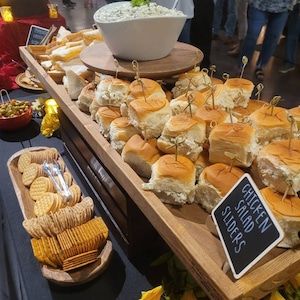 a table filled with lots of sandwiches and crackers next to bowls of dips