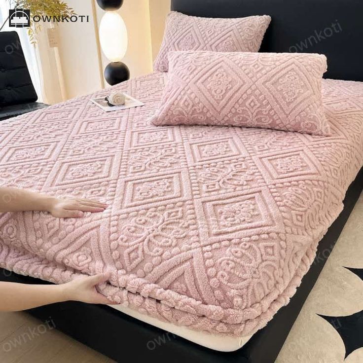 a woman laying on top of a bed covered in pink blankets and pillows with black stars