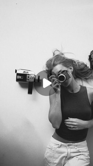 a woman holding a camera and taking a selfie in front of a wall mounted mirror