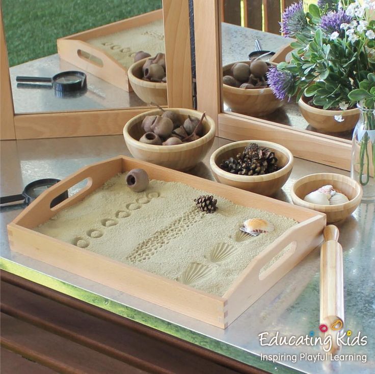 three wooden bowls filled with sand on top of a table next to mirrors and flowers