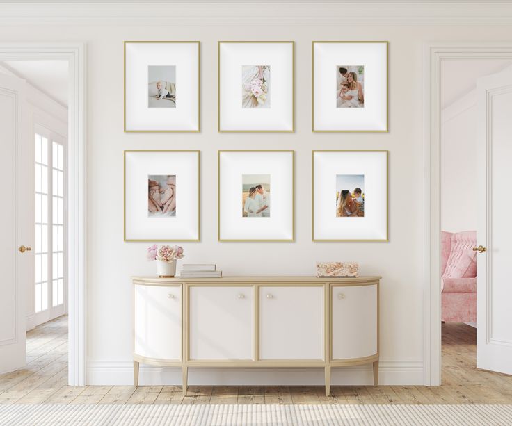 a white room with framed pictures on the wall and a table in front of it