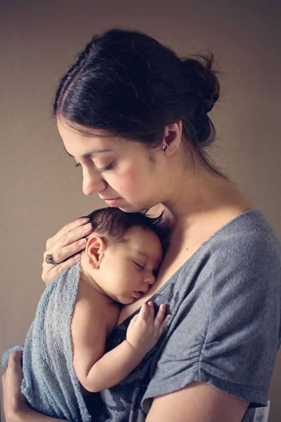 a woman is holding a baby in her arms while she holds the infant's head