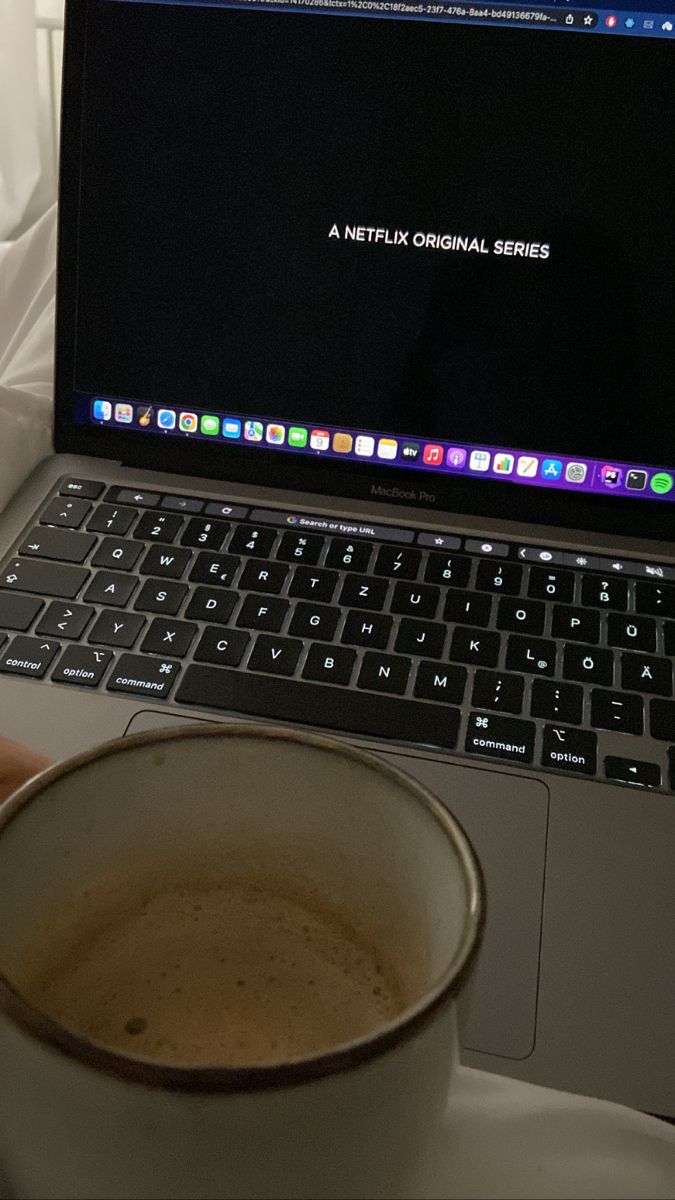 a cup of coffee sitting in front of a laptop computer