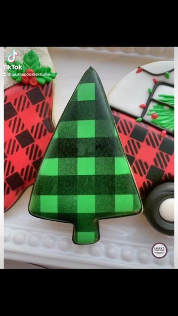 a decorated christmas tree cookie sitting on top of a white plate next to other cookies