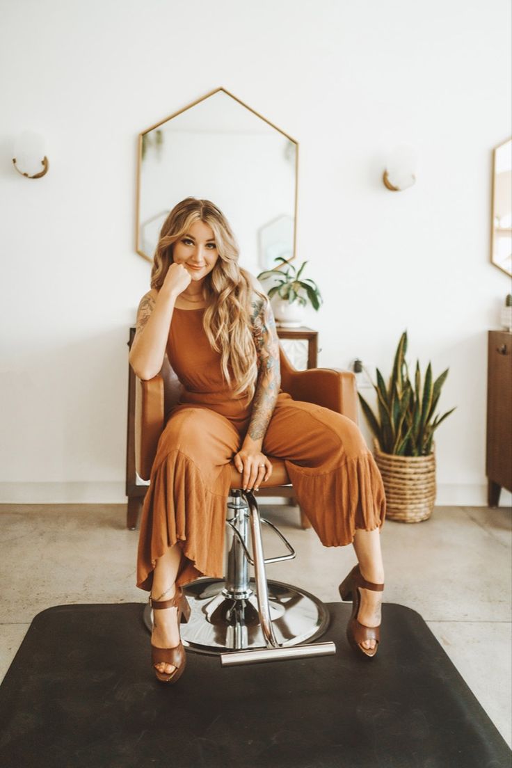 a woman sitting on top of a chair in front of a mirror and potted plant