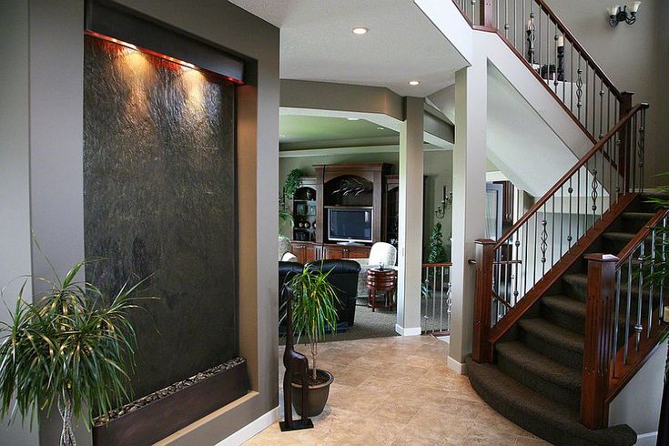 an entry way with stairs, potted plants and a painting on the wall behind it