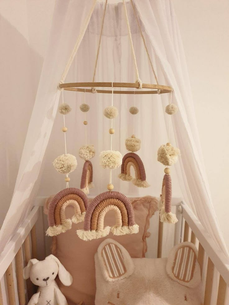 a baby crib with a teddy bear in it and some decorations hanging from the ceiling