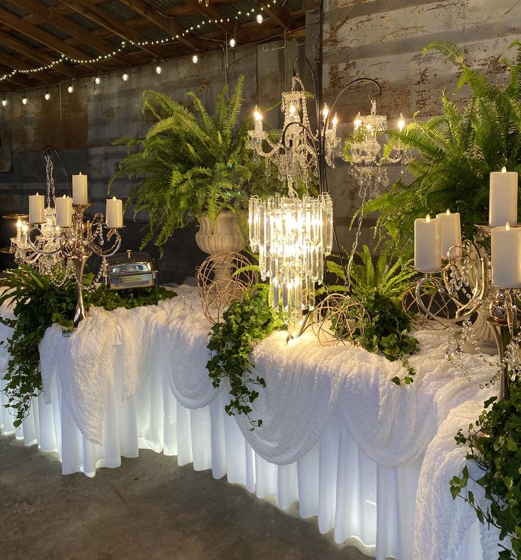 an arrangement of candles and greenery on a table at a wedding or reception venue