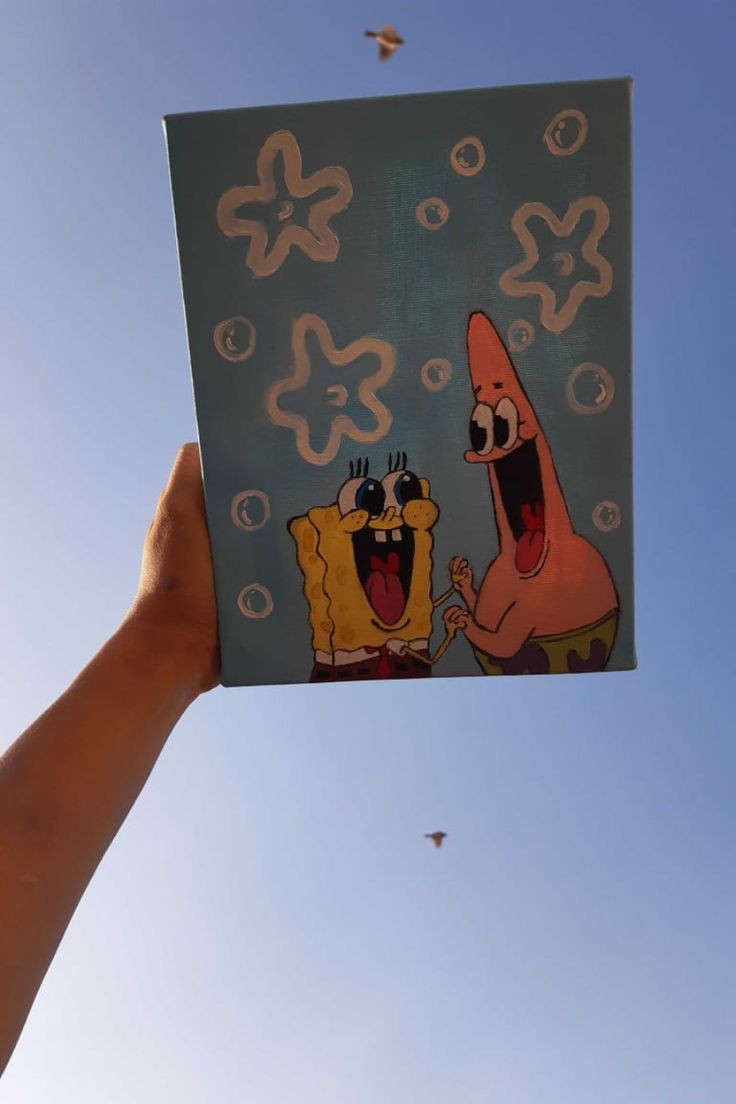 someone is holding up a card with spongebob and patrick on it in the air