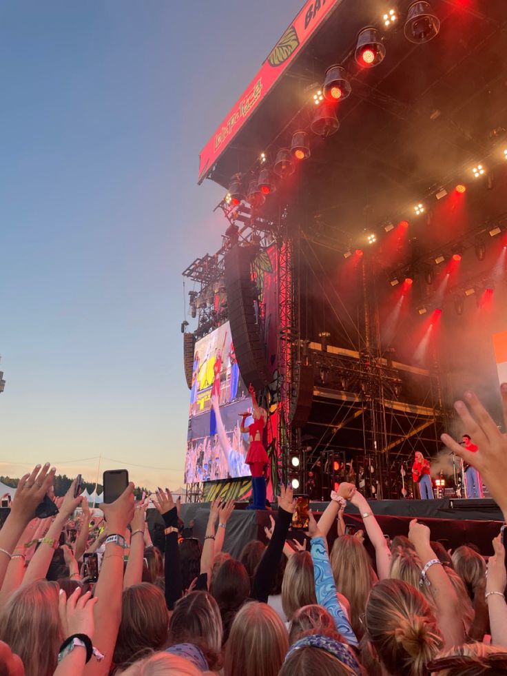 a large group of people standing on top of a stage with their hands in the air