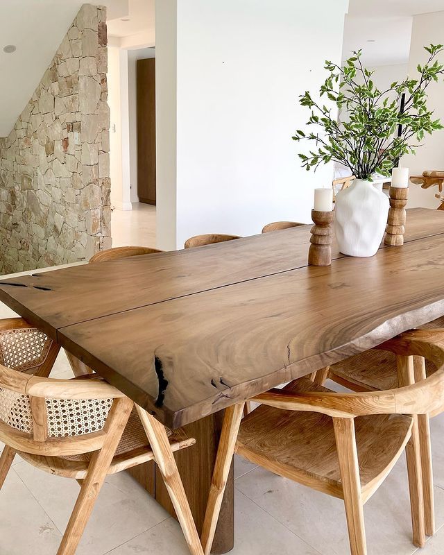 a wooden table with chairs around it and a vase on the table next to it