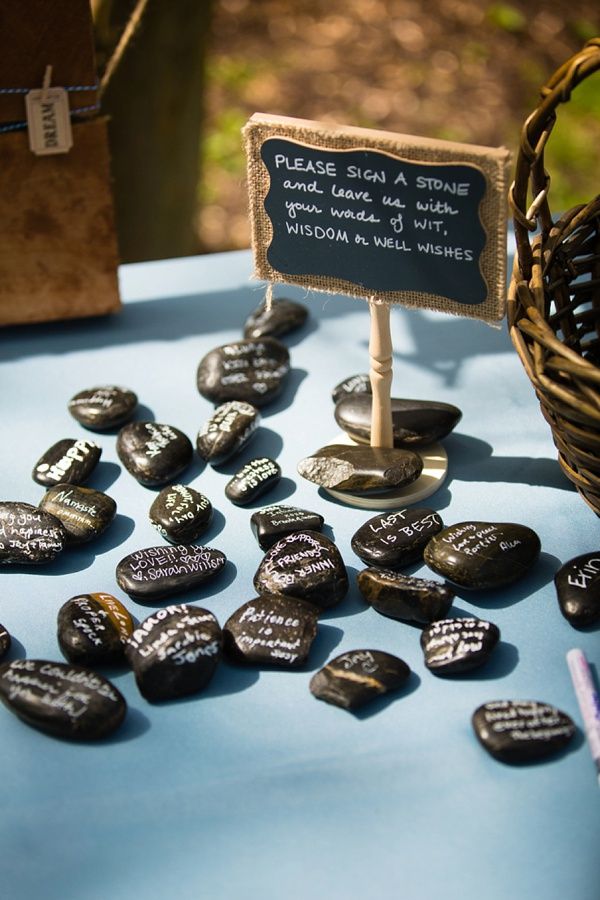 a table topped with lots of black rocks and a sign that says please sigh a smile