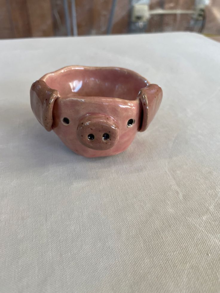 a small pig shaped bowl sitting on top of a white tablecloth covered table cloth