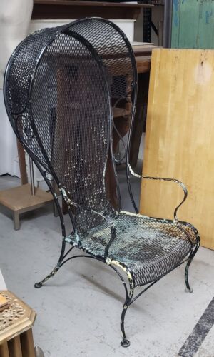 an iron chair sitting on top of a floor next to a wooden box and other items