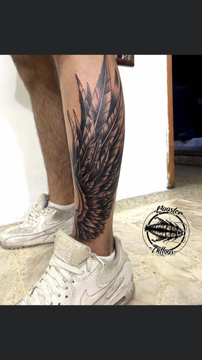 a man's leg with an angel wing tattoo on it