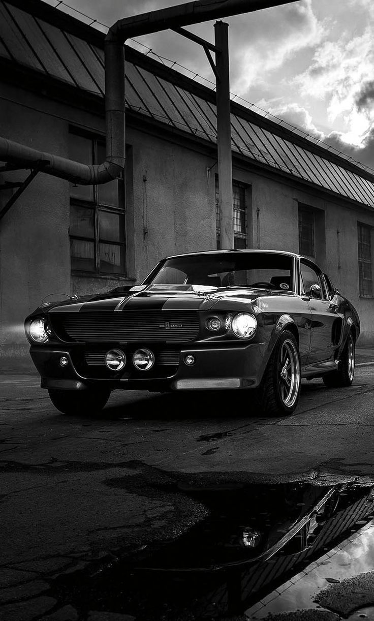 a black and white photo of a car parked in front of a building