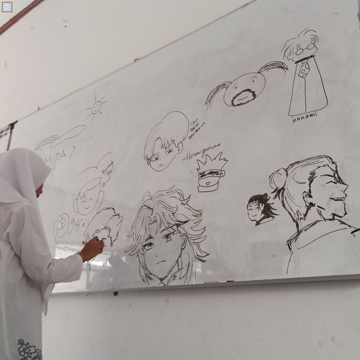 a woman is drawing on a whiteboard with black marker and some drawings behind her