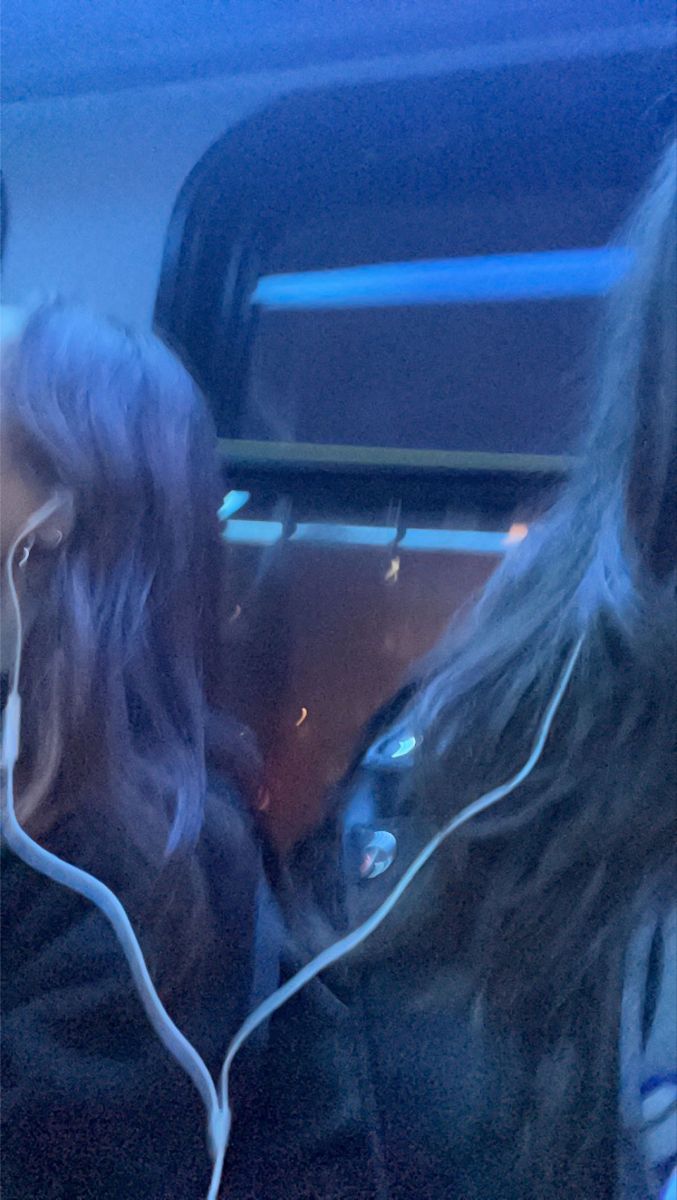 two women sitting on a bus with headphones in their ears