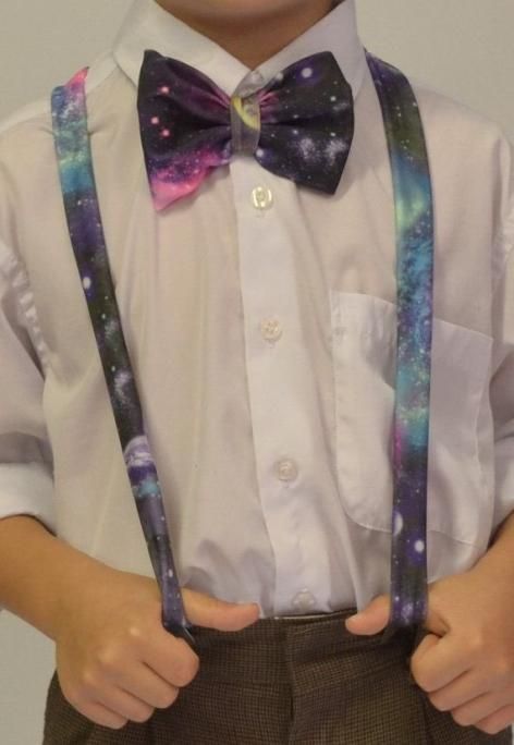 a young boy wearing suspenders and a bow tie holding his hands in his pockets