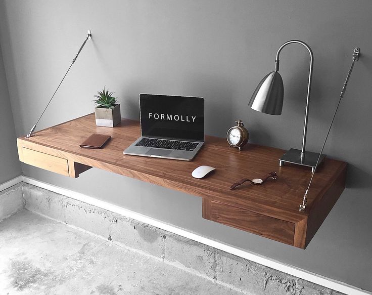 a laptop computer sitting on top of a wooden desk next to a lamp and potted plant