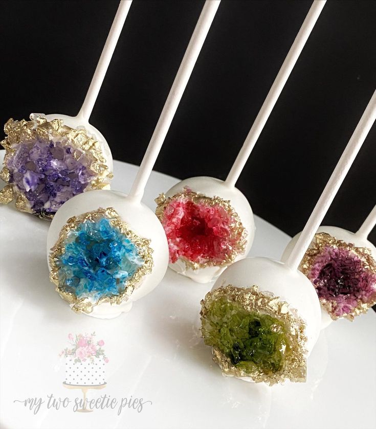 four cake pops with different colored toppings on them