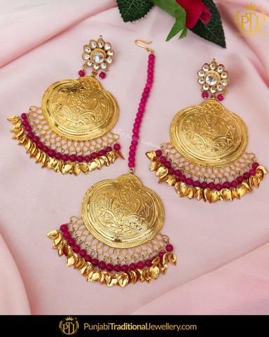 two pairs of gold and red beaded earrings on pink fabric with flowers in the background