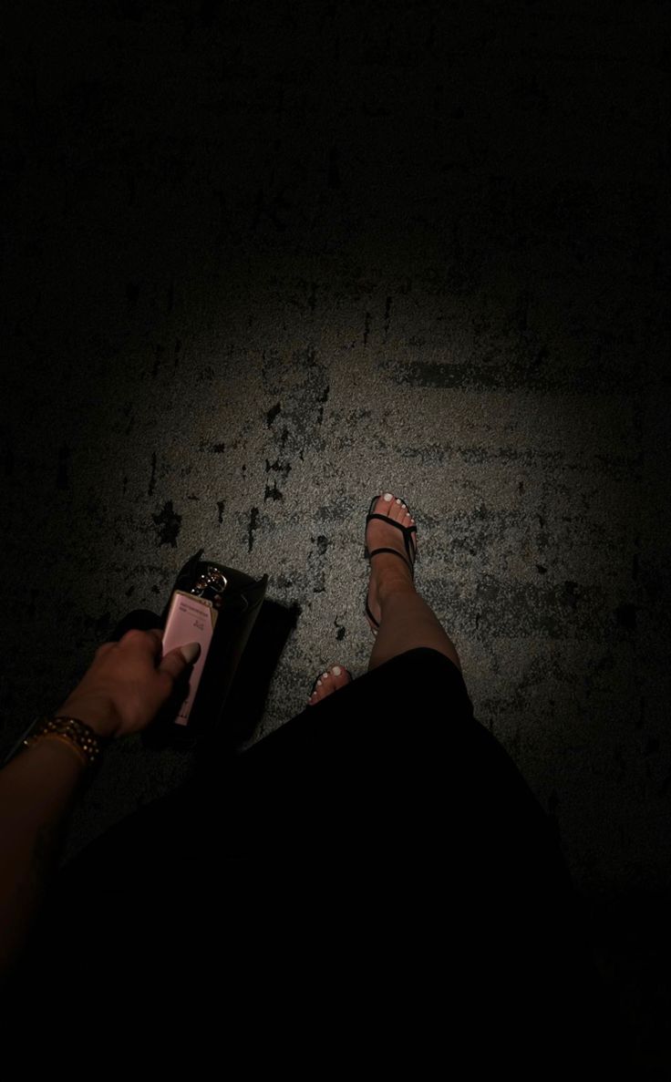 a person is standing in the dark with their feet on a remote control and there are only one persons legs visible