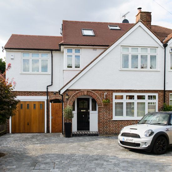 a white car parked in front of a large brick house with two garage doors and windows