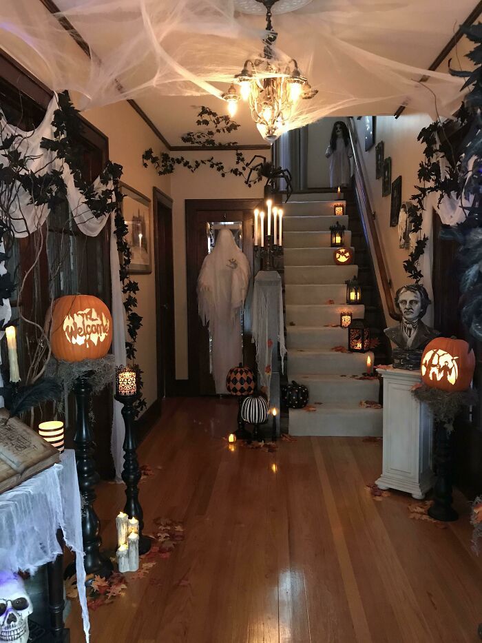 a hallway decorated for halloween with pumpkins and ghost heads hanging from the ceiling, candles lit up on the stairs