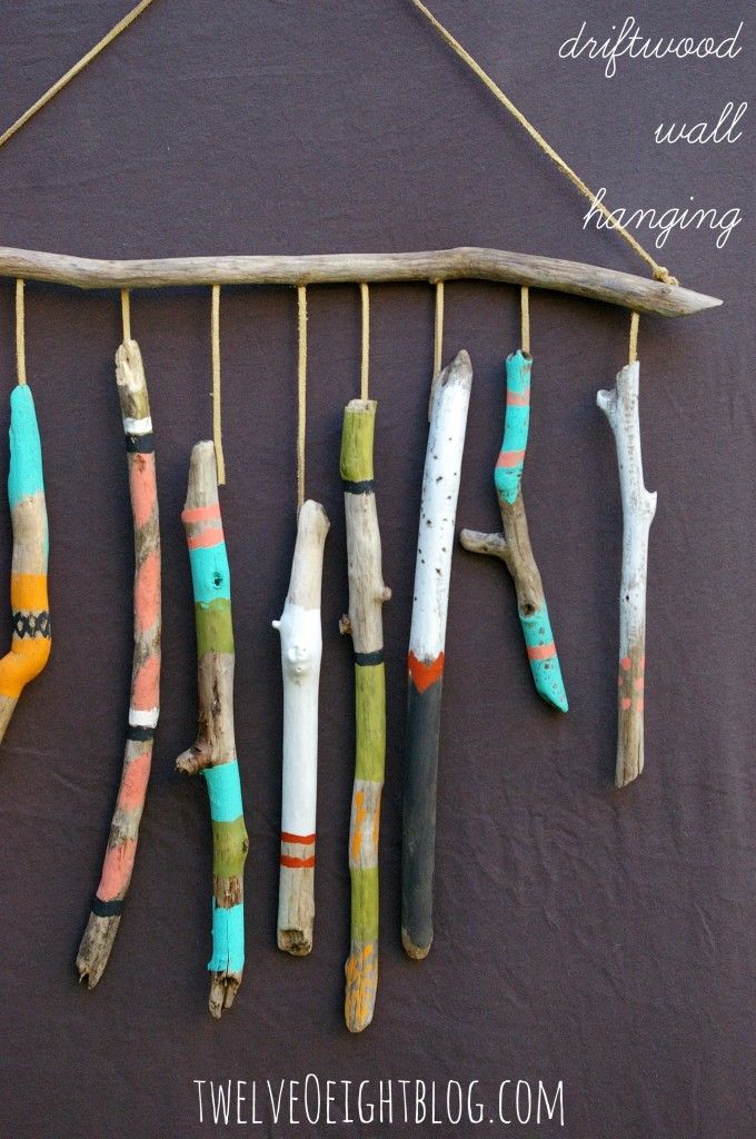 some driftwood sticks are hanging on the wall and have been painted with different colors