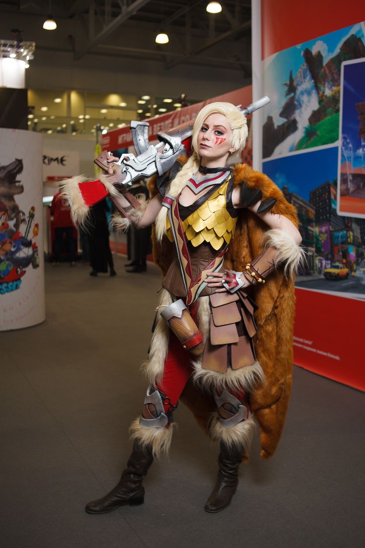 a woman dressed in costume standing next to a red and white wall with pictures on it