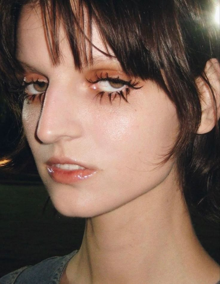 a close up of a person with eyeliners on their face and hair in the background