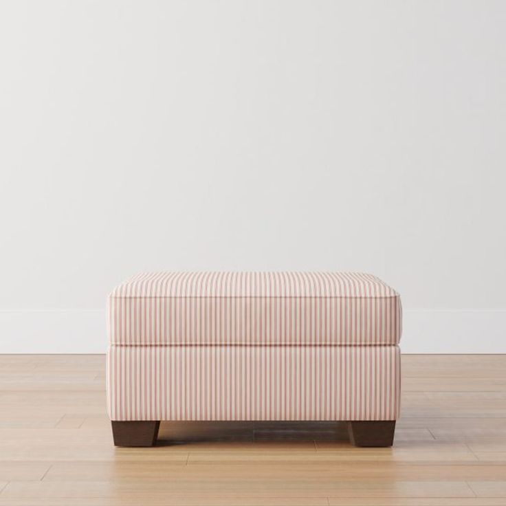 an upholstered footstool sitting on top of a hard wood floor next to a white wall