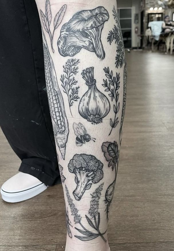 a person's leg with tattoos on it and various vegetables in the middle of their legs