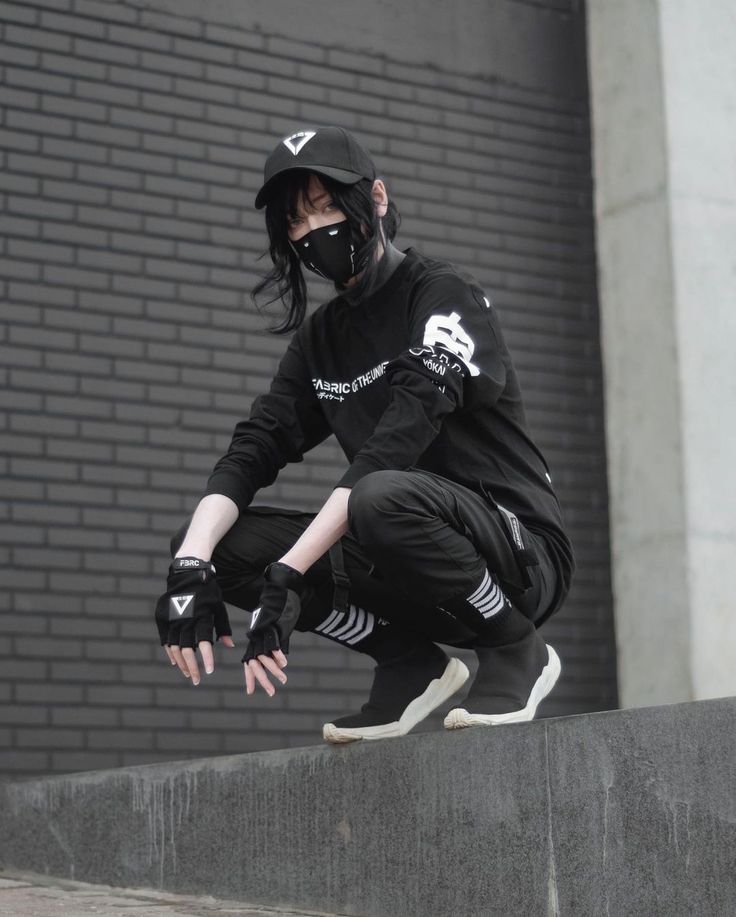 a man in black clothes and mask riding a skateboard down a cement wall next to a brick building