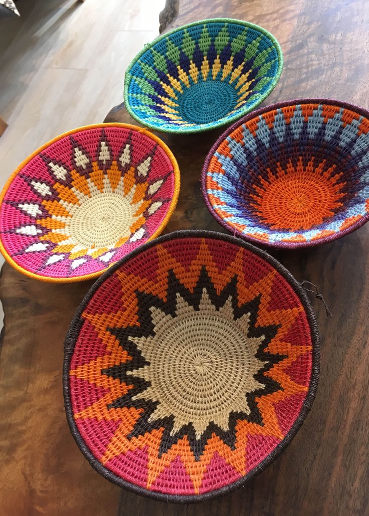 four woven baskets sitting on top of a wooden table