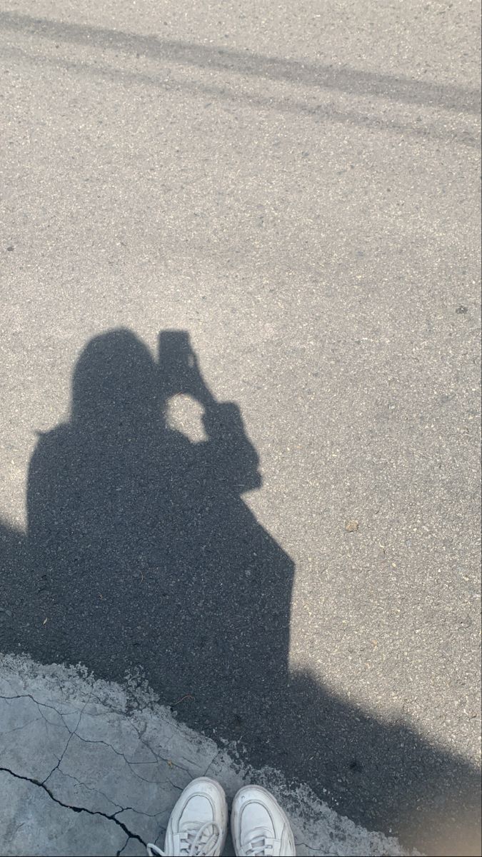 the shadow of a person standing next to a motorcycle