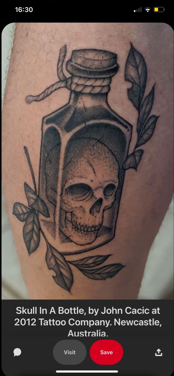 a tattoo with a skull and a bottle on the leg that has leaves around it