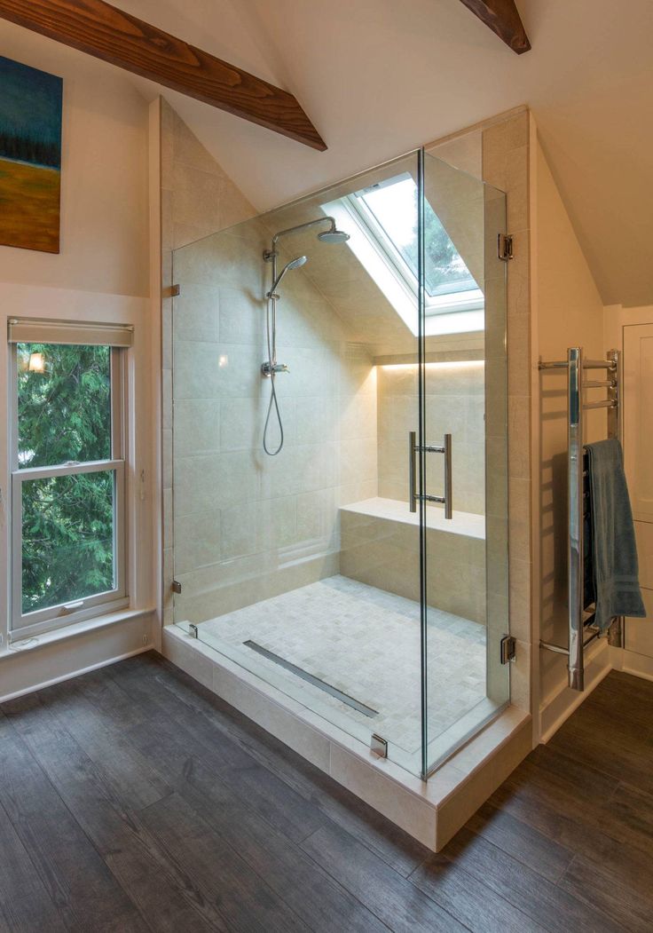 a bathroom with a walk in shower next to a window and wooden floored walls