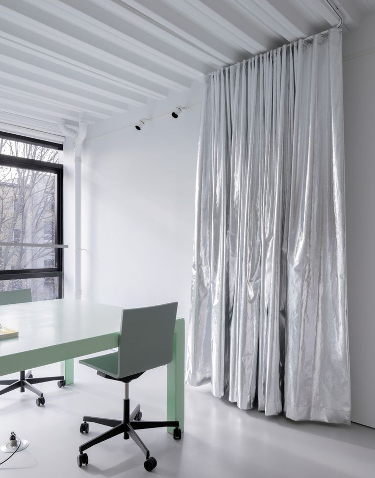 an office with a desk and chair in front of a window that has curtains on it