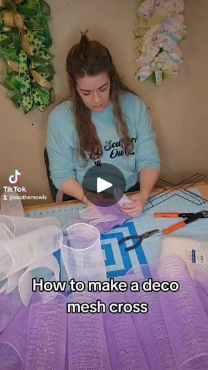 a woman sitting at a table working on some crafting supplies with scissors and yarn