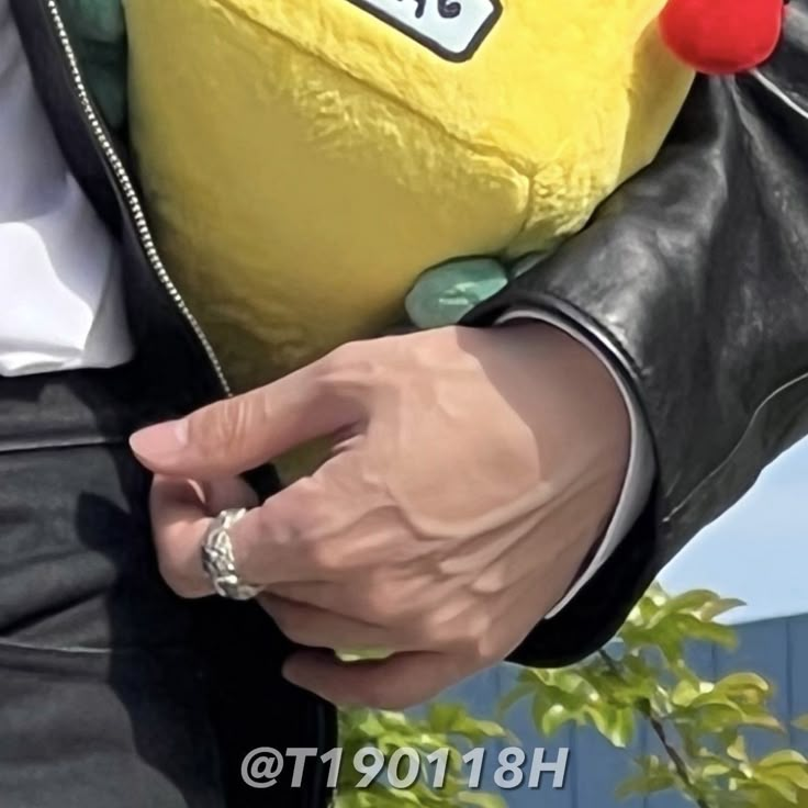 a person in a black jacket holding a yellow stuffed animal