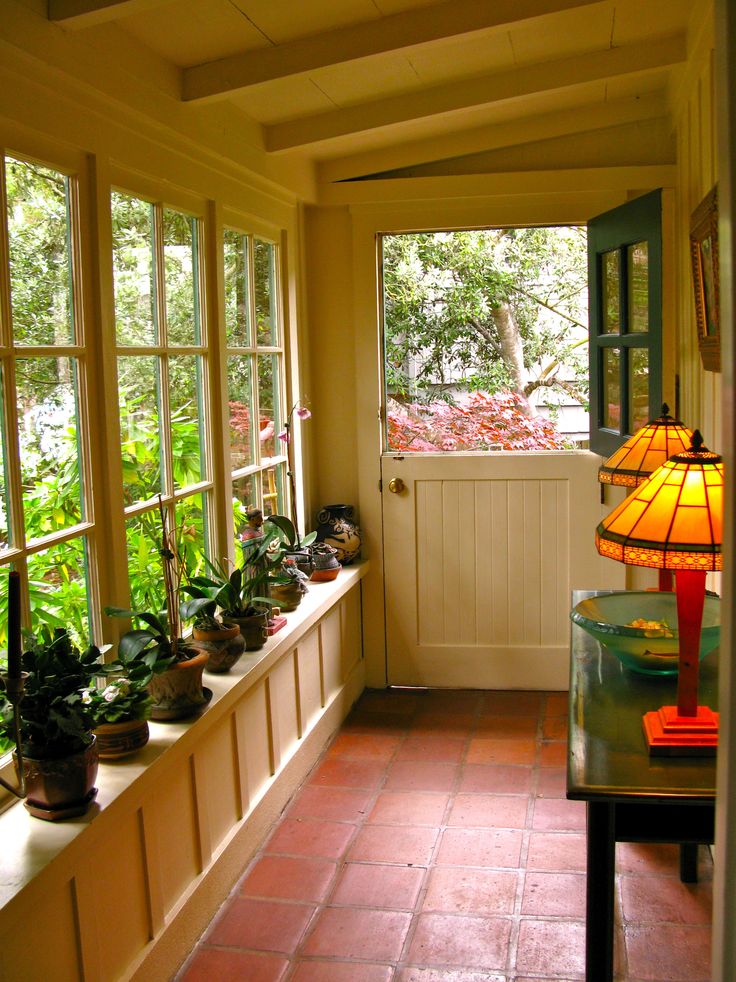 a sun room filled with lots of plants next to a lamp on a window sill